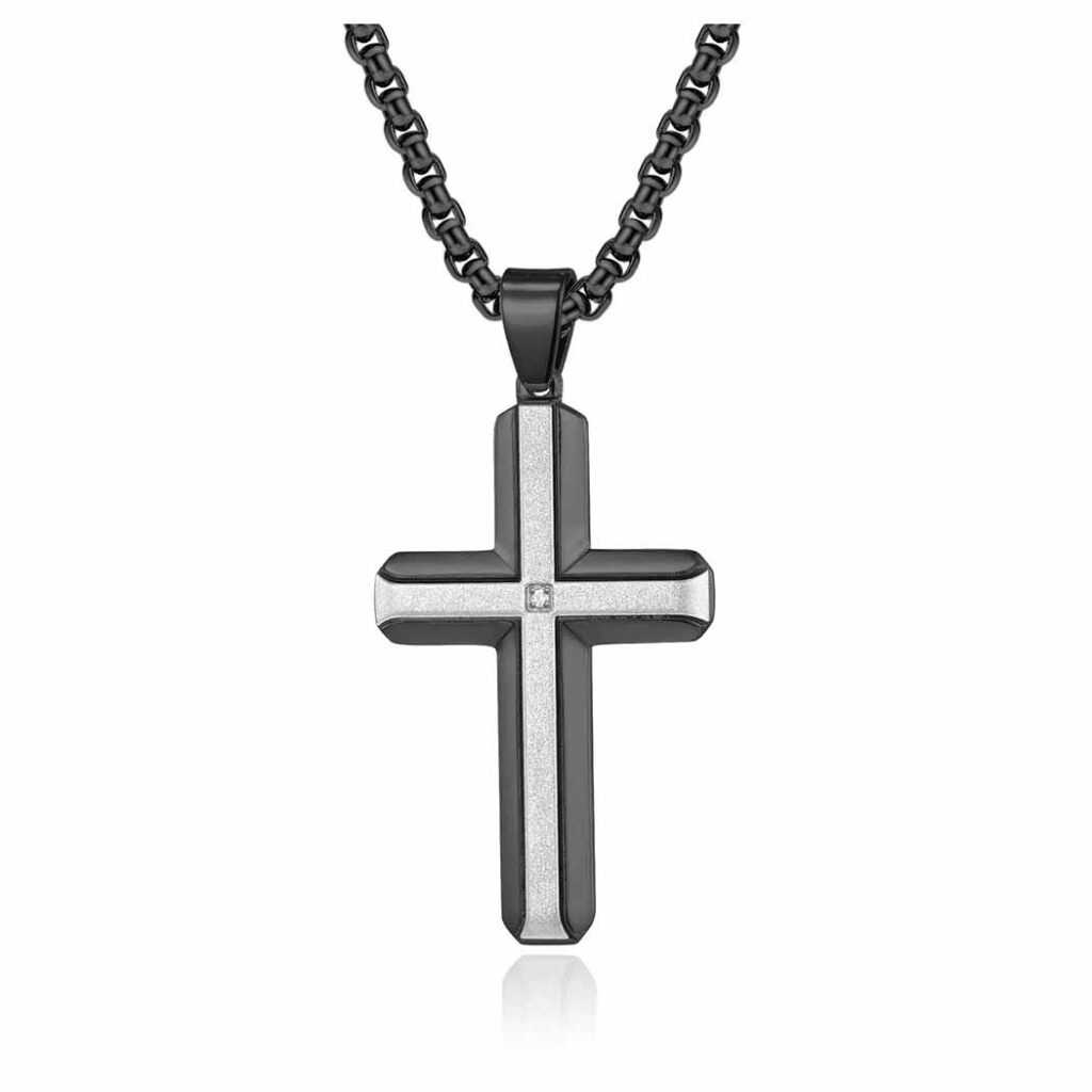 A contemporary cross pendant with a glittering sandblasted texture and a single central gemstone, hanging from a chunky dark metal chain against a white background.