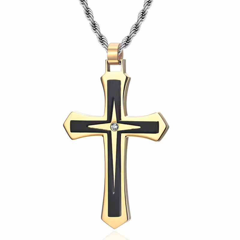 A two-toned cross pendant featuring gold and black design elements with a central gemstone, suspended from a twisted silver chain, presented against a white background.