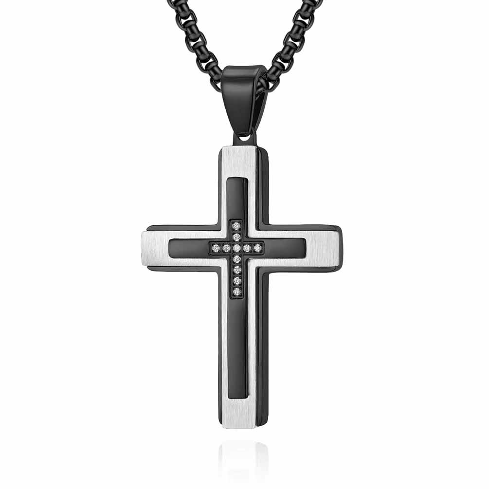 A brushed silver cross pendant with a glossy black accent and a smaller inlaid cross adorned with crystals, hanging from a bold black chain, displayed against a white backdrop.