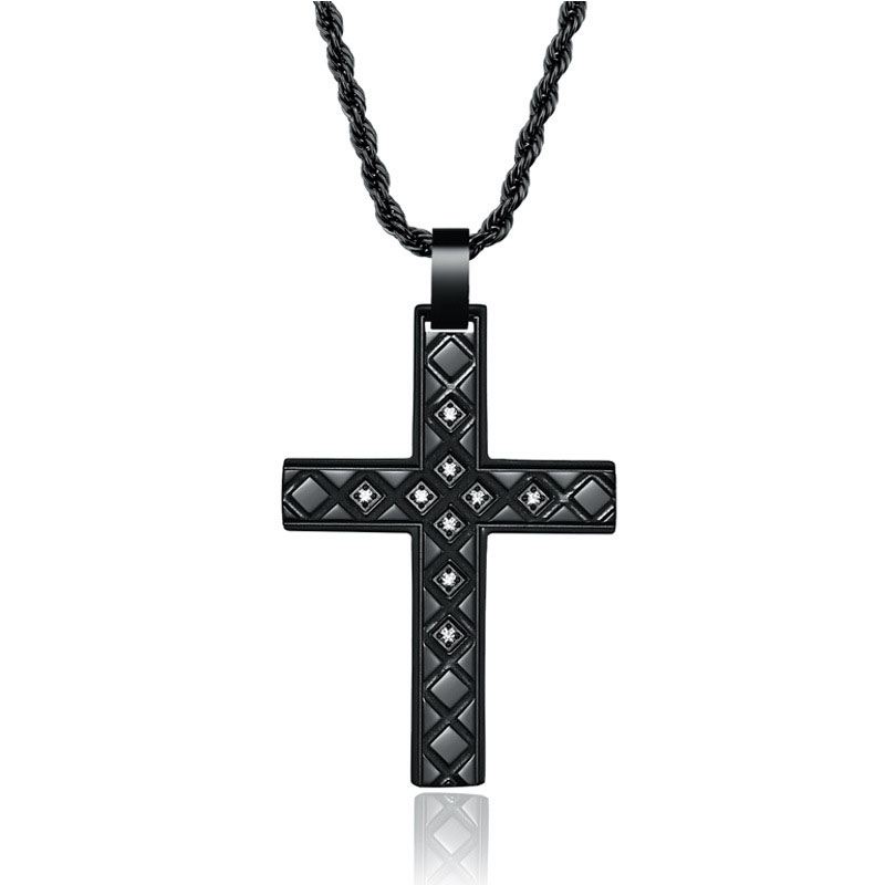 A detailed black cross pendant adorned with sparkling crystals in diamond-shaped patterns, suspended from a twisted black chain, set against a white backdrop.